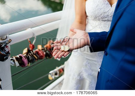 Gold wedding lock in the form of heart in the hands of the bride and groom.