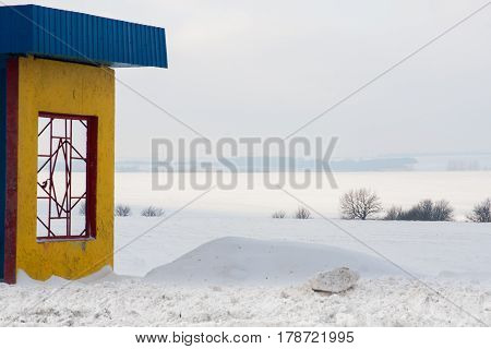 A colorful rural bus stop with snowy fields in the winter