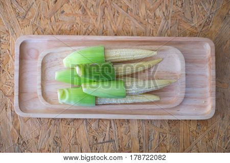 Top view of fresh young corn in wooden tray