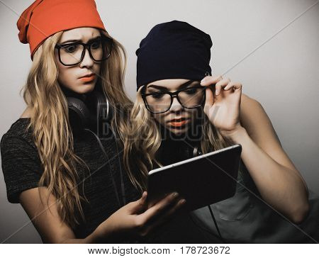 two hipster girls friends use digital tablet, studio shot over gray vackground