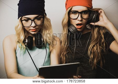 two hipster girls friends use digital tablet, studio shot over gray vackground