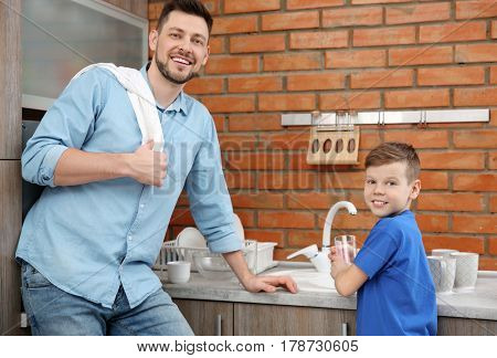 Dad and son doing the washing up in kitchen