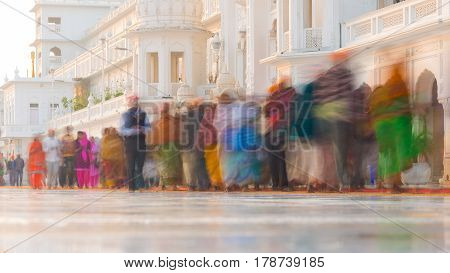 Tourists and worshipper walking inside the Golden Temple complex at Amritsar Punjab India the most sacred icon and worship place of Sikh religion. Blurred motion long exposure.