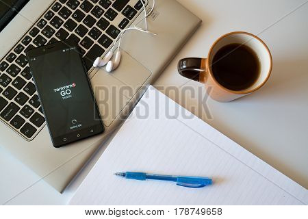 Nitra, Slovakia, march 28, 2017: TomTom go application in a mobile phone screen. Workplace with a laptop, an earphones, notepad and coffee.