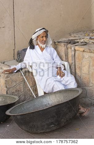 Nizwa Oma 24th March 2017: old Omani man selling old copper cooking dishes at the market