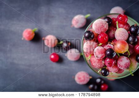 Frozen And Fresh Berries In A Glass Pial On A Black Background.