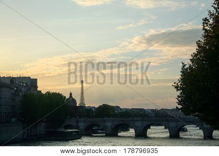 Typical view of Paris with Pont-Neuf and Seine river at sunset. Eiffel Tower can be seen in the background