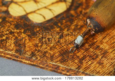 Close up shot of pyrography pen over burned wood