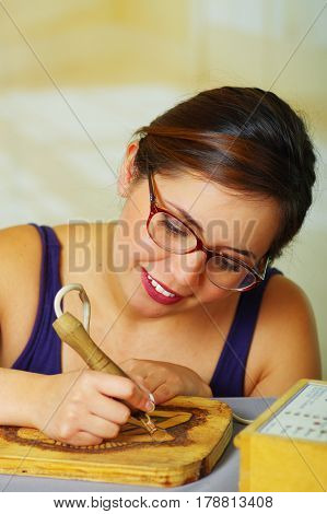 Beautiful young woman wood burning with pyrography pen