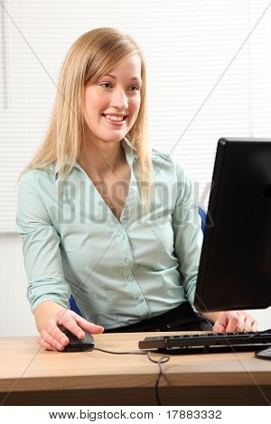 Belle femme blonde bien remplie à l'ordinateur de bureau