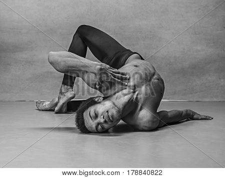 The male ballet dancer dancing over gray background. Colorless image
