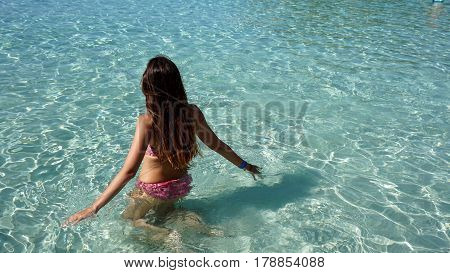 Girl playing with water in a crystal clear beach