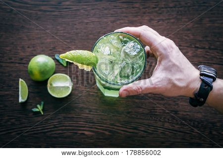 Mojito in the barman's hand over the table on which lies lime