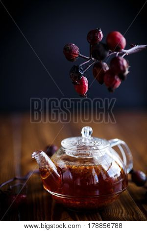 Dried red rose hips and tea on a black background