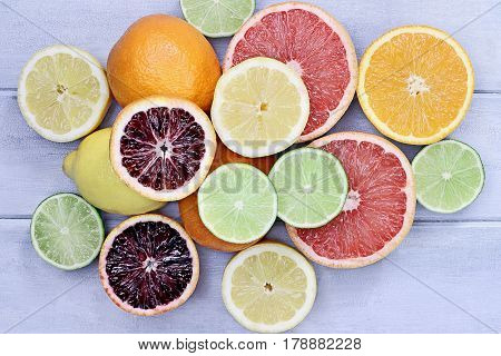 Variety of citrus fruits (orange blood oranges lemons grapefruits and limes) over a blue wood table top rustic background. Image shot from overhead.