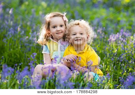 Kids Playing In Blooming Garden With Bluebell Flowers