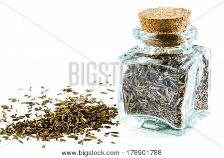 Dry cumin in glass bottle and heap of cumin isolated on white background. Closeup macro shot.