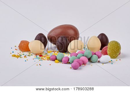 Sweets on white background. Chocolate eggs and sprinkles. How to make candies.