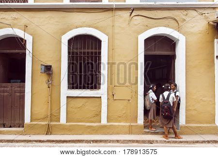 PANJIM, INDIA - FEB 25, 2017: Schoolgirls talking in front of old school building in historical indian town on February 25, 2017. Near 5 million tourists visit Goa annually