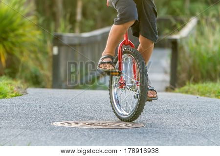 outdoor portrait of young boy riding a unicycle (one wheel bike) on natural background