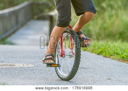 outdoor portrait of young boy riding a unicycle (one wheel bike) on natural background