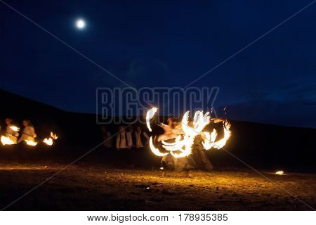 Amazing Impressive Freeze light fire show with fire trails highly in mountains with a moon in a colorful blue sky