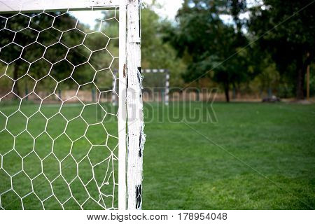 Soccer football net background over green grass and blurry stadium. Background of soccer football goal in stadium on match day