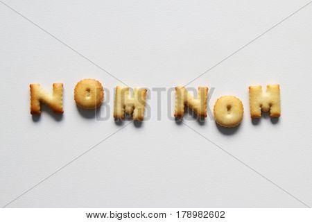 An Inscription From The Cookies On The White Background. Text – Nom Nom.
