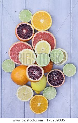 Variety of citrus fruits (orange blood oranges lemons grapefruits and limes) over a blue wood table top rustic background. Image shot from overhead.