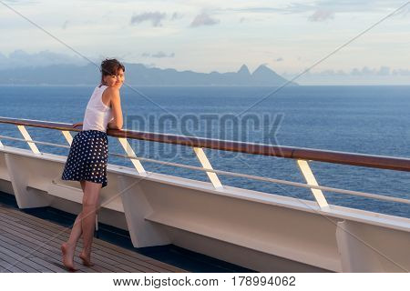 young woman in dress stands on the deck of cruise liner