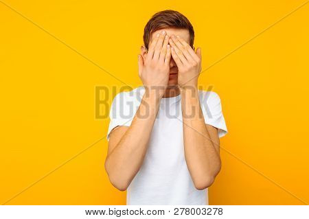 Portrait Of A Frightened Man With Glasses, The Guy Closed His Eyes With His Hands For Fear, On A Yel