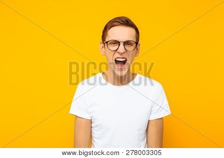 Irritated Man In Glasses, A Man Is Shouting Aggressively, On A Yellow Background