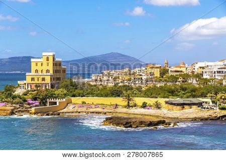 Mediterranean Seacoast In Alghero City, Sardinia, Italy. Spring Flowers And Trees On Foreground, Col