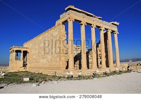 Caryatid Statues On The Porch Of The Erechtheion On The Acropolis In Athens, Greece With Blue Sky An