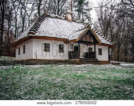 Ukrainian Village Hut With Thatched Roof. First Snow