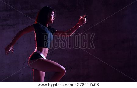 Young Sport Woman Running Jogging In Gyn In Blue And Pink Neon Light On Dark Wall Background