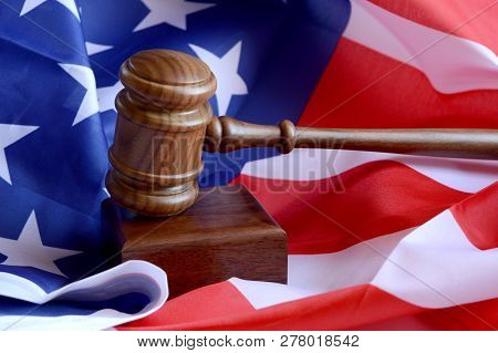 A Closeup View Of A Gavel Resting Ontop Of An American Flag For Law And Order Concepts.