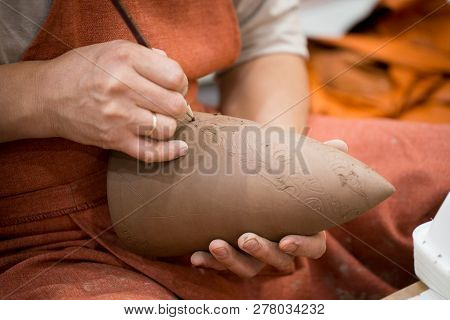 Ceramic Workshop, The Master Puts Otnament On Unfired Earthenware Jug. Close-up Of Master Hands. Mad