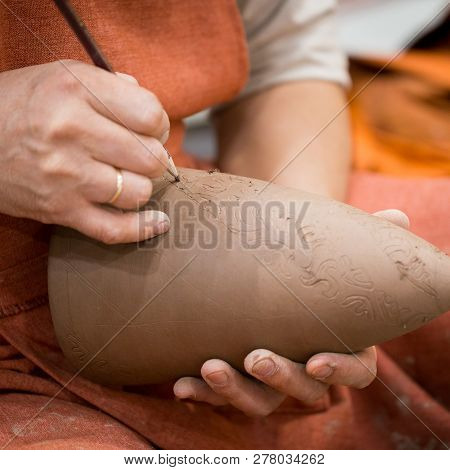 Ceramic Workshop, The Master Puts Otnament On Unfired Earthenware Jug. Close-up Of Master Hands. Mad