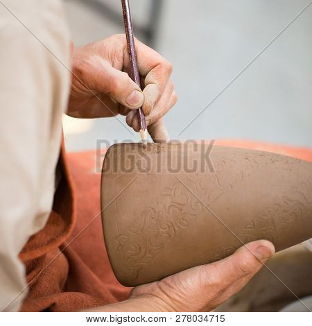 Ceramic Workshop, The Master Puts Otnament On Unfired Earthenware Jug. Close-up Of Master Hands. Mad