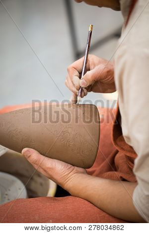 Ceramic Workshop, The Master Puts Otnament On Unfired Earthenware Jug. Close-up Of Master Hands. Mad