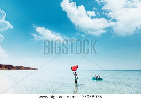 Friends on lilo chilling in the clear sea water. Girls and boy relaxing on inflatable ring on the beach. Summer vacations, idyllic scene.