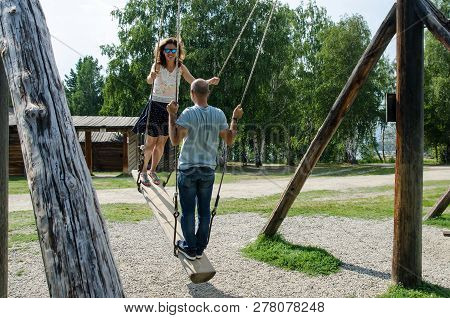 Talczy, Irkutskaya Oblast, Russia - 7 August 2017, Couple On A Wooden Swing Near The Tree And Old Wo