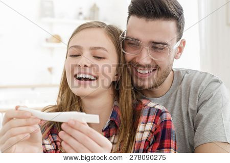 Young Family Looking At Positive Result Of Pregnancy Test, Going To Have Baby Together, Feeling Happ