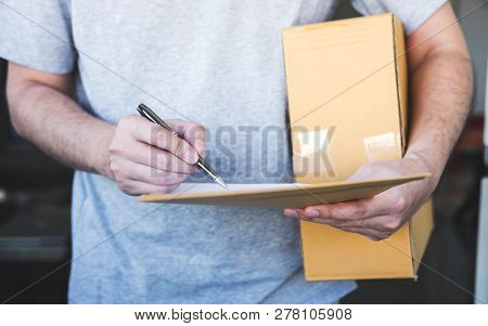 Delivery Mail Man Giving Parcel Box To Recipient And Signature Form, Young Owner Signing Receipt Of 