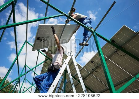 Professional Mounters Team Installing Solar Batteries On Metallic Carcass. Modern Solution For Natur