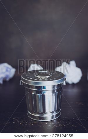 Garbage Bin On Desk Setting And Scrunched Paper Balls Around It, Concept Of Drafting And Struggling 