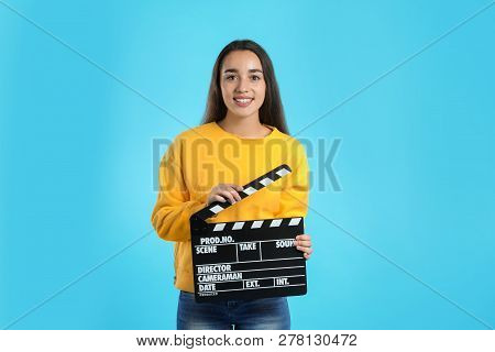 Woman With Clapperboard On Color Background. Cinema Show