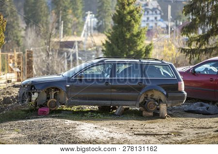 Red Car Parked In Recreation Zone And Old Rusty Broken Trash Car After Crash Accident Without Wheels