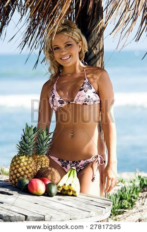 Ragazza bionda sexy del bikini in spiaggia in bikini rosa e marrone di Swimbay sotto un ombrello palapus w